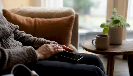 Hands holding smartphone in home office