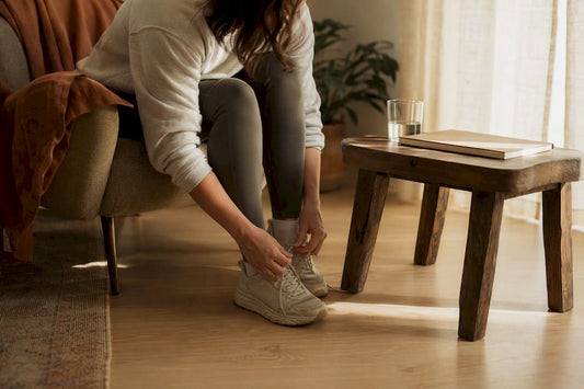 Person tying shoes by bed in morning light