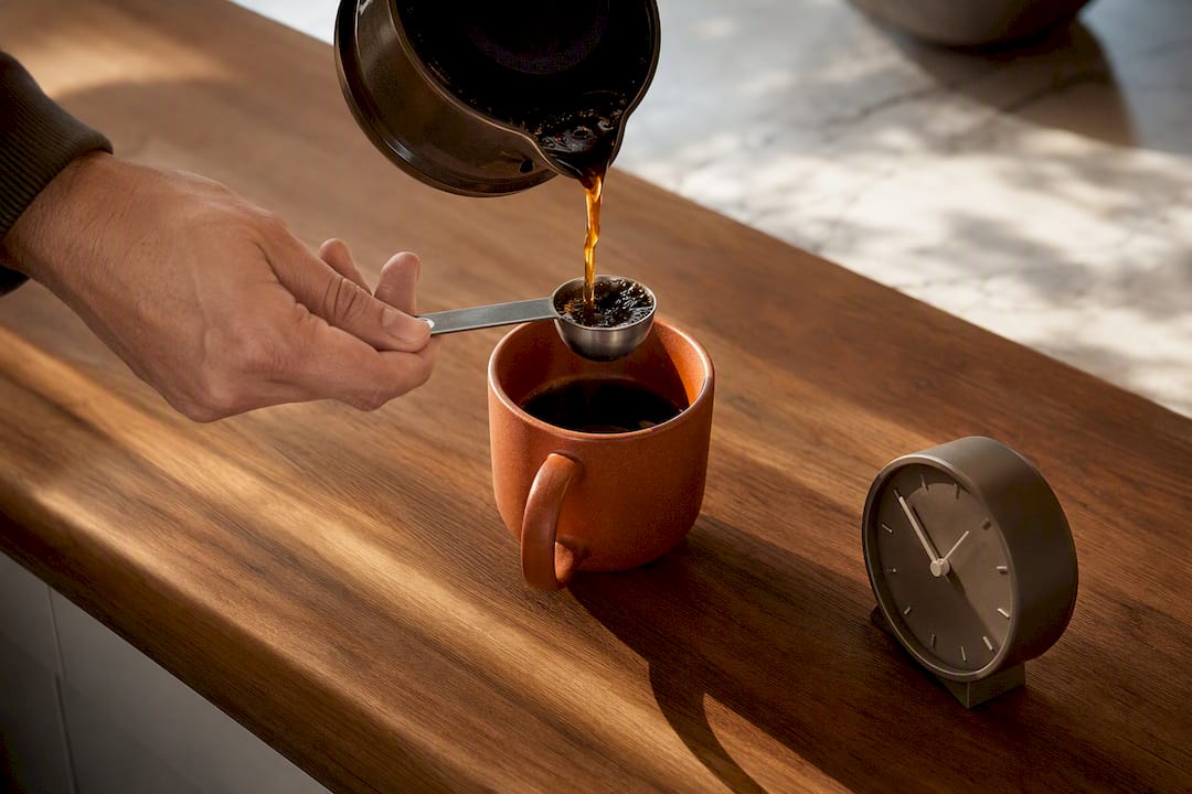 Coffee cup beside clock on kitchen counter